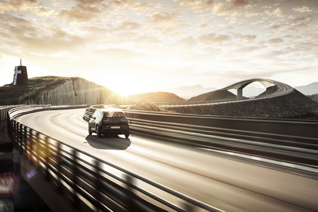 Car driving across bridge into sunset